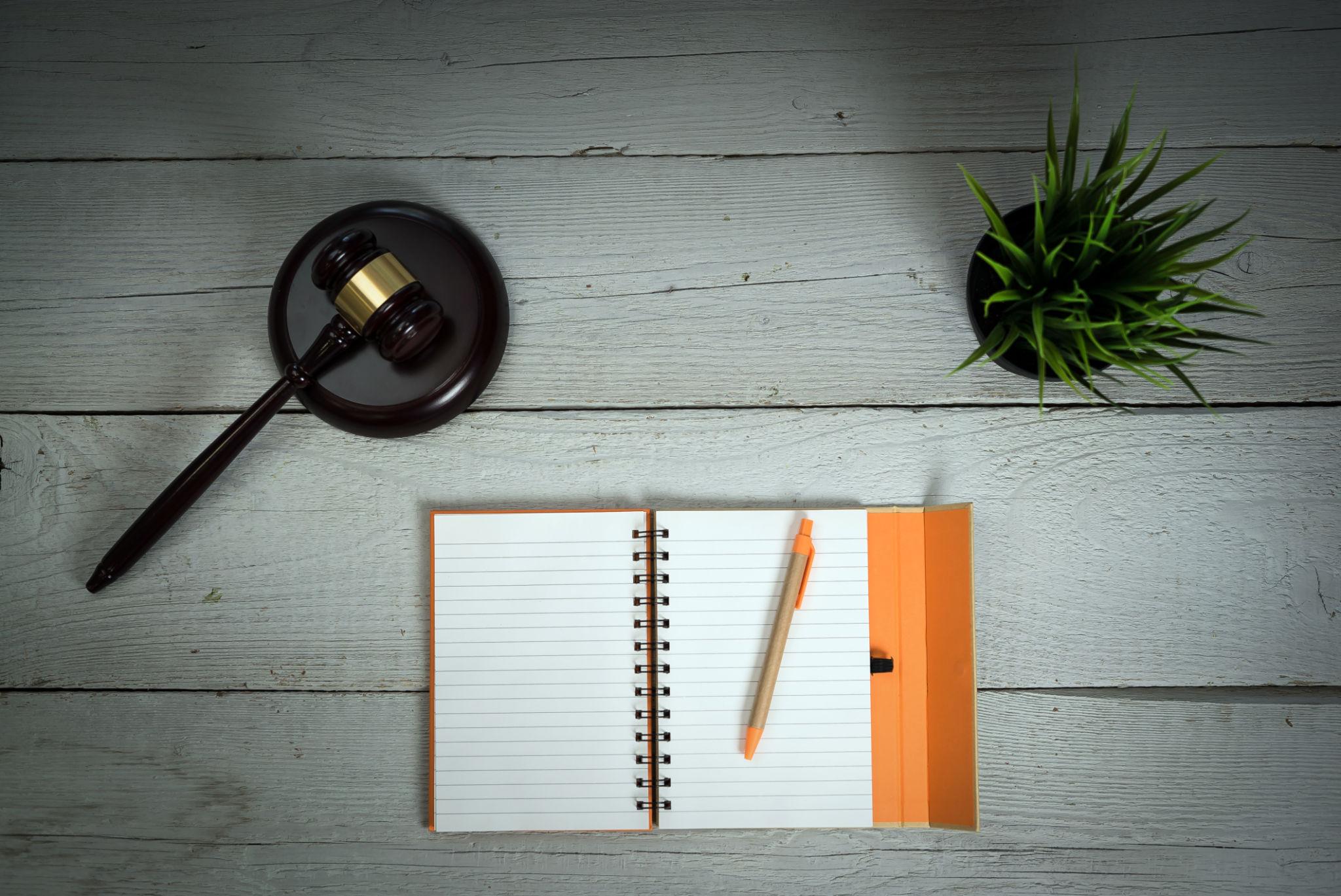A gavel, notebook, and pen arranged on a desk